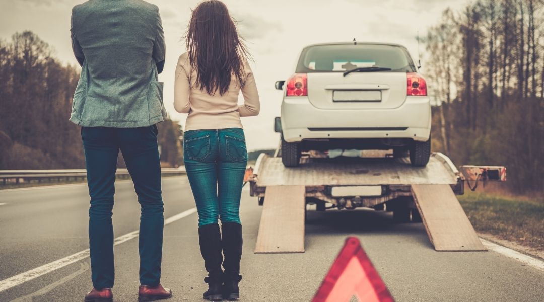 casal olhando para o carro quebrado sendo guinchado na estrada. melhor seguro para carro