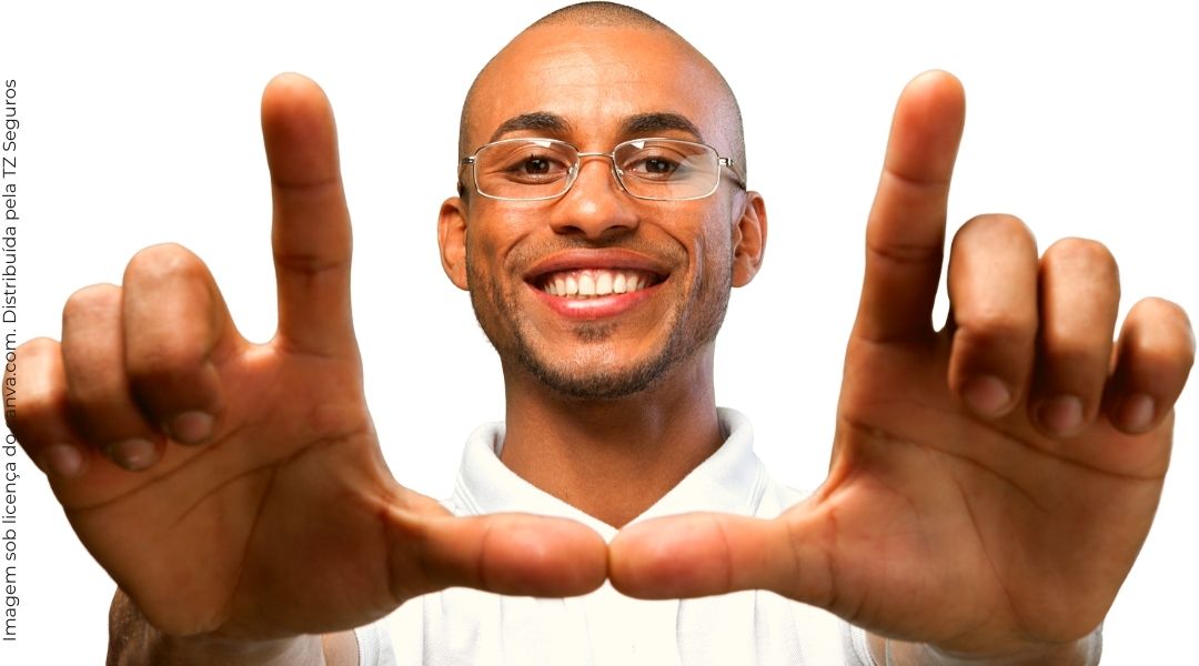Jovem de óculos, sorrindo e com as mãos para frente