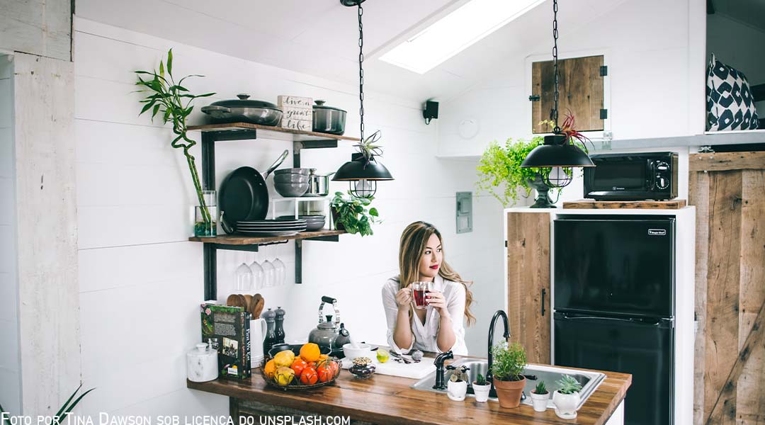 Jovem moça na cozinha de sua residência, tomando um café e imaginando algo