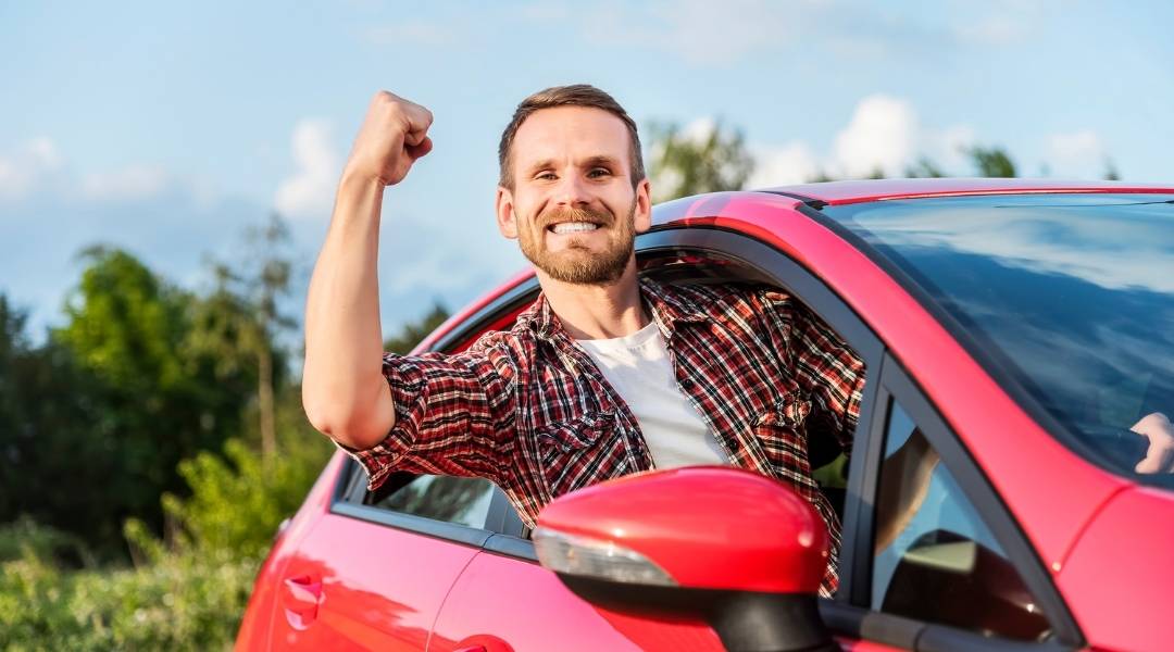 homem feliz em seu carro vermelho, ele possui um seguro automóvel e pode viajar tranquilo para o interior